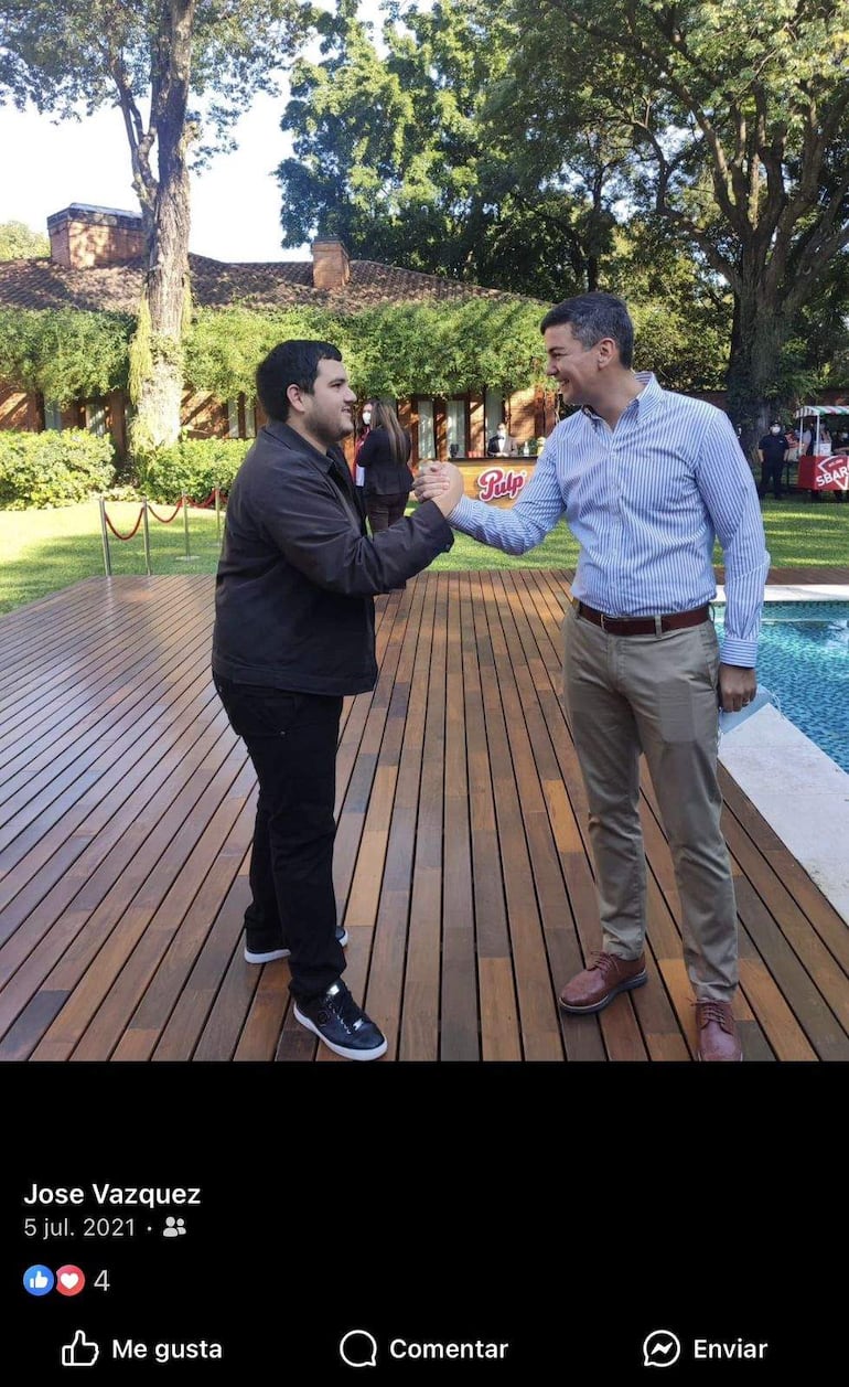 Santiago Peña Santi con chaqueta oscura y pantalón negro, sonriendo mientras saluda con el puño a un hombre con camisa a rayas.