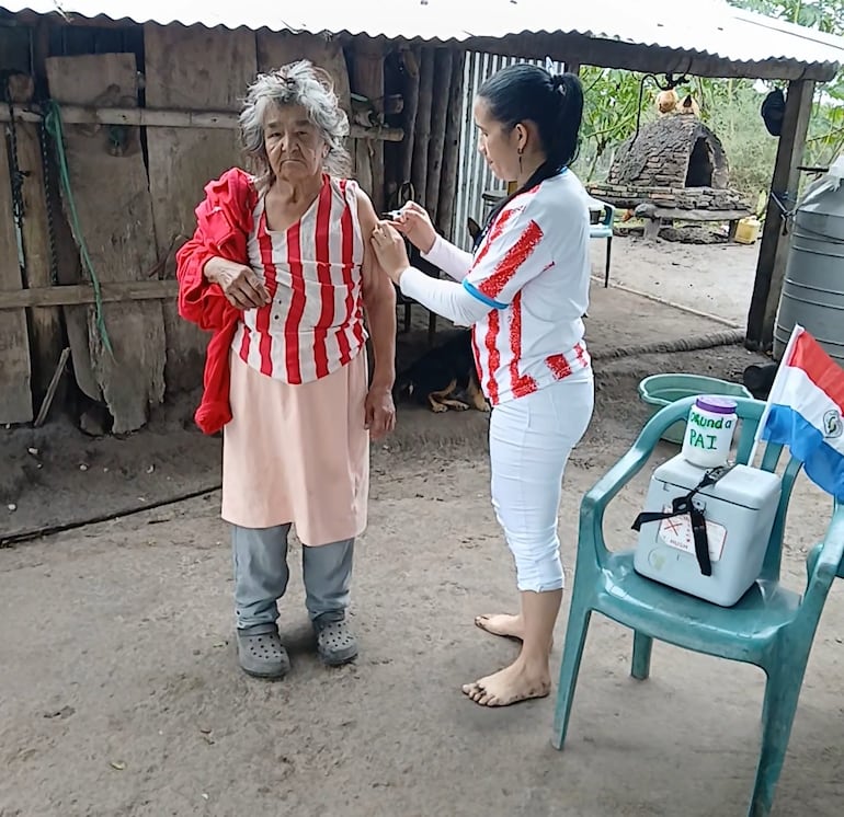La enfermera Lili Arguello aplica la vacuna contra la influenza a una persona mayor, también con la remera de la albirroja en Costa Pindó.