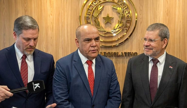 Natalicio Chase en chaqueta azul y corbata roja, Basilio Núñez con traje oscuro y Antonio Barrios con cabello canoso, en ambiente legislativo.