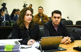 Alba Zaracho con cabello rizado y blazer negro, junto a Hernán Rivas con camisa de rayas en sala de audiencias.