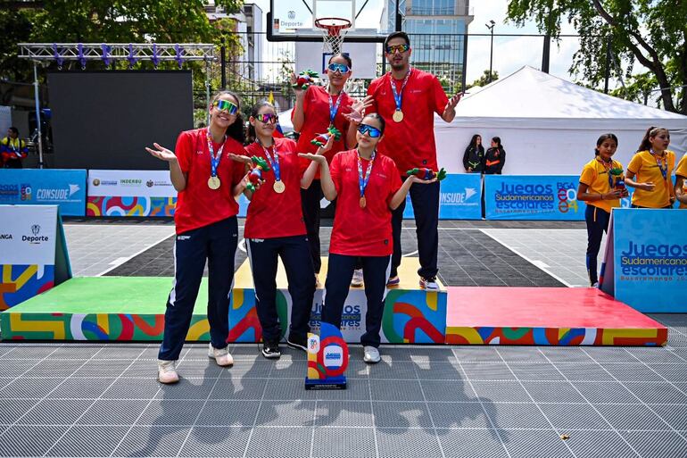 Las niñas del baloncesto 3x3 posan con su entrenador en lo alto del podio sudamericano.