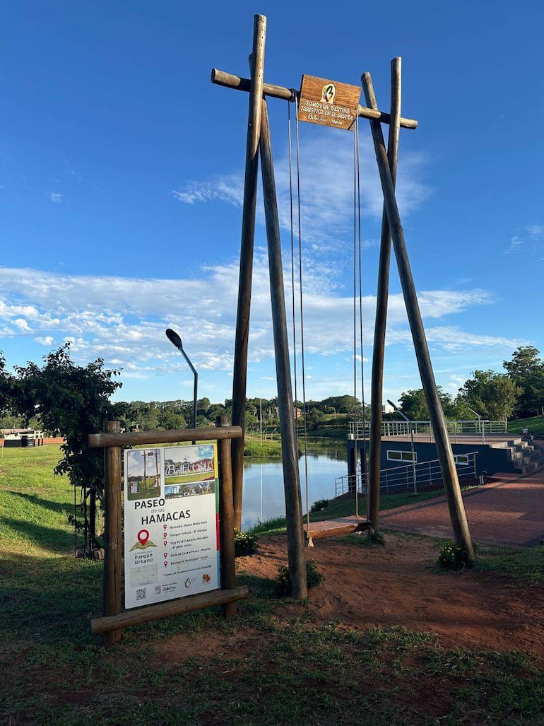 Espacio recreativo al aire libre con una estructura de hamacas de madera, rodeada de vegetación y un lago visible al fondo.
