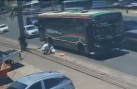 Una persona asiste a la mujer luego de la caída desde el bus en movimiento.