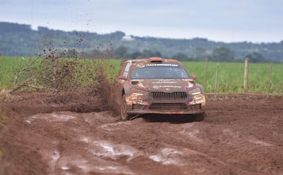 Coche de competición levantando barro en terreno natural mientras compite en el rally.