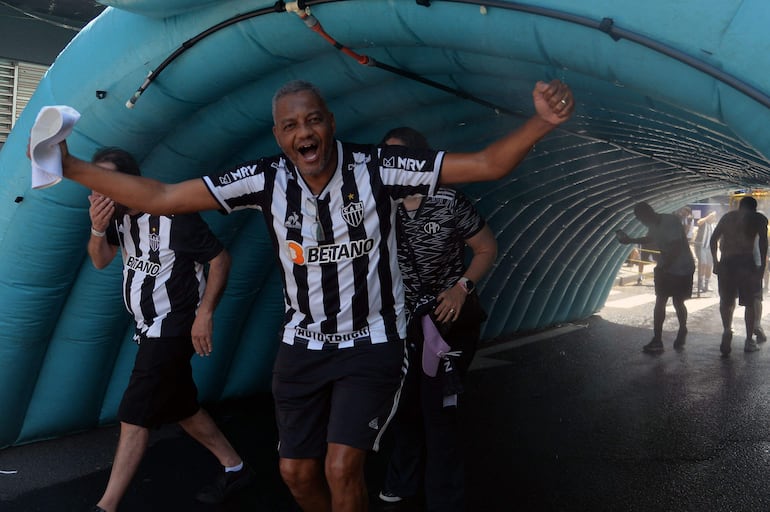 Hinchas de Atlético Mineiro cruzan un túnel de agua para refrescarse ante el intenso calor.