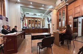 Alicia Pucheta con cabello largo y Diego Crispín Candia Melgarejo en audiencia, ambiente formal con paredes de madera.