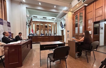 Alicia Pucheta con cabello largo y Diego Crispín Candia Melgarejo en audiencia, ambiente formal con paredes de madera.