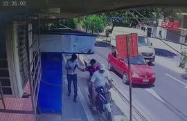 El ladrón,  con la remera azulgrana agarra el celular de las manos de la víctima, mientras su cómplice acelera la marcha para escapar del lugar.