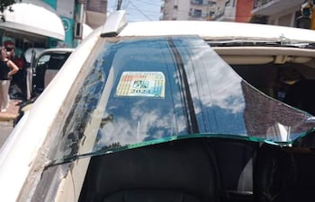 Vehículo con cristal roto y etiqueta visible, rodeado de edificios en una calle urbana.