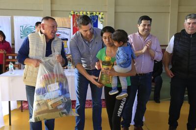 El vicepresidente de la República Pedro Alliana, junto al gobernador de Ñeembucú Victor Hugo Fornerón y el director de la EBY Luis Benítez hacen entrega de un kits de víveres a una pobladora de San Juan de Ñeembucú.