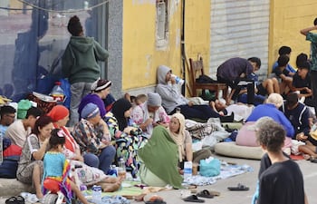 Cientos de inmigrantes marroquíes descansan en las calles de Ceuta, este lunes. La vigilancia en el entorno de la frontera del Tarajal, tanto por vía marítima como terrestre, así como los nuevos medios de contención en la zona con la instalación de una barrera en el mar han reducido al mínimo las entradas a nado desde Marruecos.