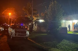 Policía en calle con camionetas blancas y personas reunidas frente a una casa iluminada en Cambyretá.