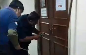 Funcionarios intentan abrir la puerta del depósito en el que la hermana de Yamy Nal debería cumplir funciones.