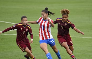 Claudia Martínez intenta escaparse de la marca de dos jugadoras venezolanas, durante el partido disputado hoy en Villa Elisa.