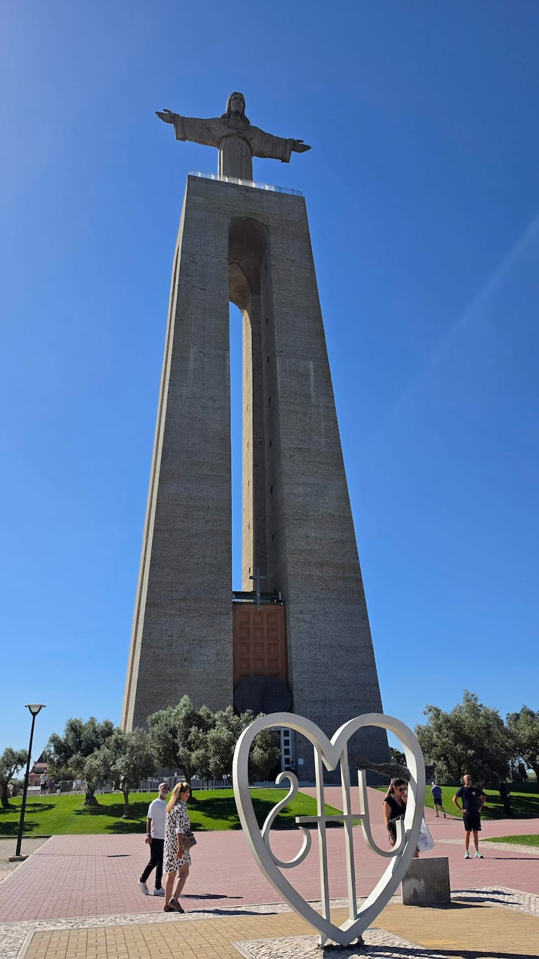 Un grupo de turistas camina frente al Cristo Rei, disfrutando del clima y el paisaje en Lisboa.