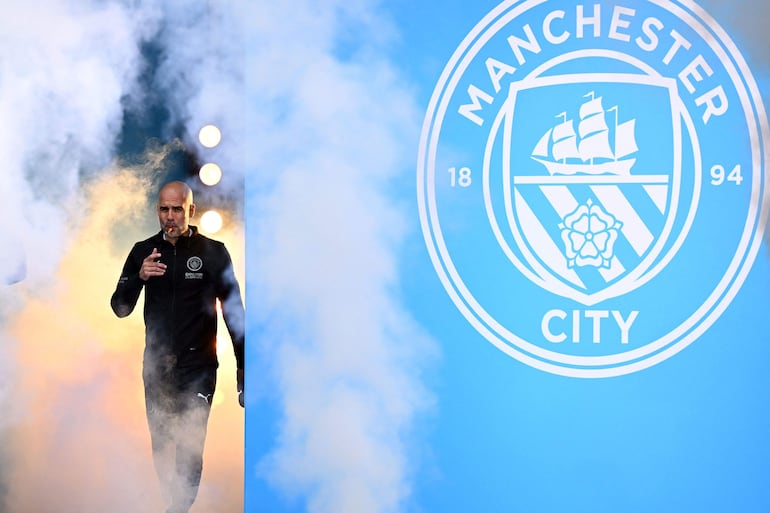 El entrenador español del Manchester City, Pep Guardiola, fuma un puro mientras asiste a un evento para aficionados junto con miembros de la plantilla del Manchester City tras un desfile en autobús descapotable por Manchester, en el noroeste de Inglaterra.