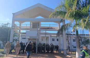 Funcionarios de seguridad y policías en uniforme en la entrada de la penitenciaría, bajo un cielo despejado.