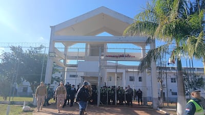 Funcionarios de seguridad y policías en uniforme en la entrada de la penitenciaría, bajo un cielo despejado.