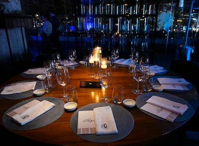 Mesa circular elegante con manteles neutros, velas encendidas, copas de vino y platos en un ambiente acogedor.