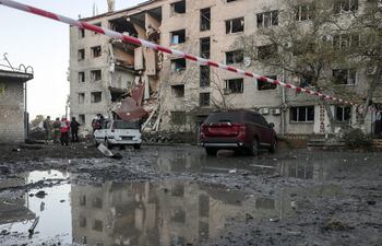 Rescatistas ucranianos y pobladores locales permanecen en el lugar de un ataque ruso contra una zona residencial en Zaporiya, en el sureste de Ucrania