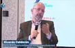 Ricardo Calderón sentado, con micrófono en mano, vistiendo saco oscuro y suéter blanco, hablando en un evento de periodismo.