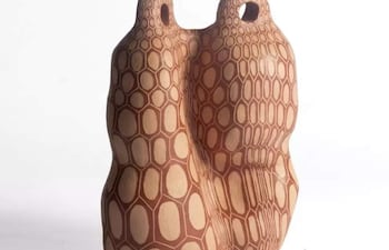 Escultura de cerámica con patrón de relieve y agujeros en la parte superior, presentada en un fondo blanco.