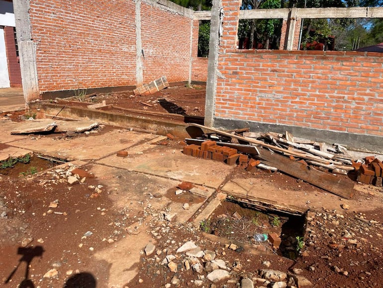 Espacio al aire libre con restos de materiales de construcción y pared de ladrillo en ruinas.