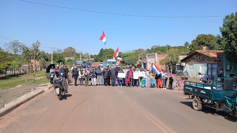 Un grupo de vecinos con banderas paraguayas, algunos luciendo tristes y otros tranquilos, se manifiestan en la calle.