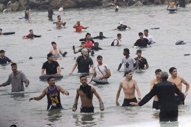 Un grupo de inmigrantes en la playa junto al paso fronterizo del Tarajal en Ceuta, ayer,  donde se han registrado violentos enfrentamientos en los perímetros fronterizos durante su intento de acceder desde Marruecos hacia Ceuta y Melilla. 
