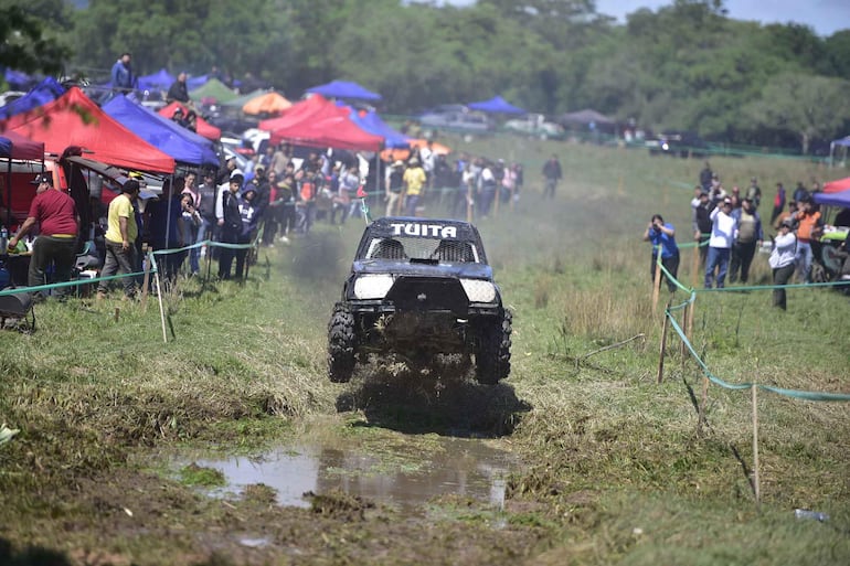 Vehículo todoterreno 'TUITA' en salto, rodeado de espectadores con expresiones de emoción en un ambiente festivo.