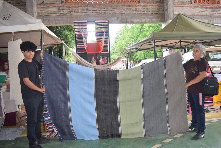 La artesana Saturnina Da Silva, acompañada de su nieto Gabriel Pérez, muestra una frazada de trapo.