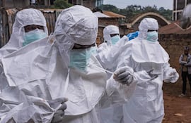 Trabajadores de la Sociedad de la Cruz Roja de Uganda se colocan trajes de protección mientras se preparan para evacuar el cuerpo de una presunta víctima de ébola en Kampala el 26 de mayo de 2026.