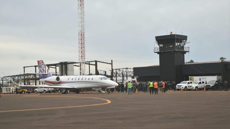 Grupo de personas en el aeropuerto con chalecos de seguridad, junto a un avión ejecutivo blanco, en un día nublado.