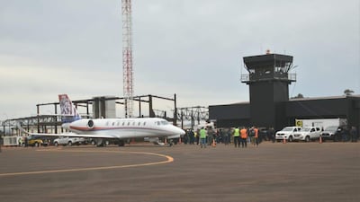 Grupo de personas en el aeropuerto con chalecos de seguridad, junto a un avión ejecutivo blanco, en un día nublado.