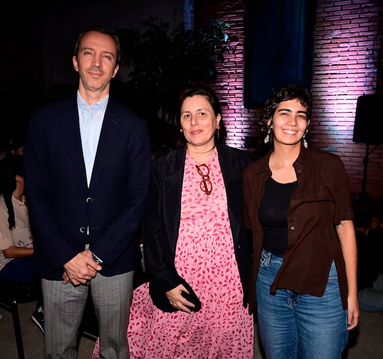 Javier Javier Parrondo Babarro con blazer oscuro, mujer central en vestido rosa y chaqueta negra, y otra mujer sonriente en blusa oscura y jeans.