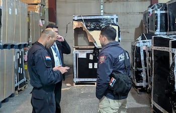 Policías y funcionarios de la terminal aérea conversan en el sitio donde se produjo el robado de mercaderías.
