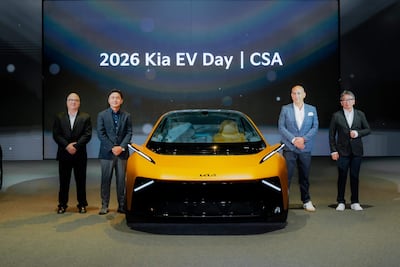 Hombres de chaqueta negra y trajes observan un automóvil eléctrico amarillo durante el Kia EV Day en un ambiente digital.