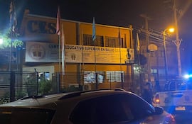 Exterior del Centro Educativo Superior en Salud CES en Ypacaraí, con un coche patrulla y un automóvil estacionado.