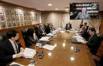 Gustavo Santander Dans y César Garay Zuccolillo en reunión formal, con trajes oscuros y banderas visibles en el fondo.