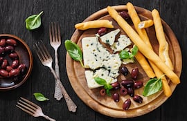 Tabla con grisines, aceitunas negras y queso azul.