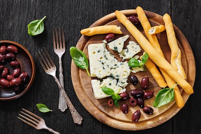 Tabla con grisines, aceitunas negras y queso azul.