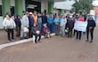 Grupo de adultos mayores en San Ignacio, con mujer al frente sosteniendo cartel sobre pensión universal, vestidos abrigados y serios.