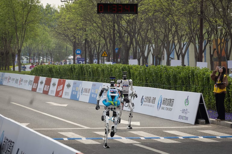 Robots humanoides cruzan la línea de meta en la segunda Beijing E-Town Half Marathon and Humanoid Robot Half Marathon, una media maratón disputada por humanos y robots humanoides, en Beijing, China, el 19 de abril de 2026.
