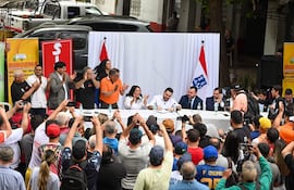 Luis Bello y Jorge Sabate aplauden mientras firmantes en mesa central celebran el contrato colectivo rodeados de banderas paraguayas.