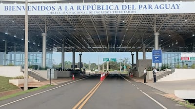 Funcionarios de seguridad en uniforme observan el tráfico en un moderno punto de control en Paraguay.