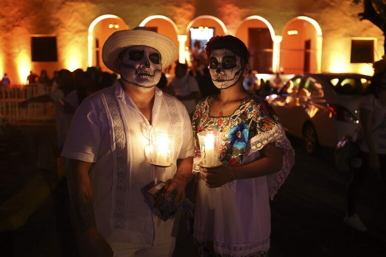 Personas pintadas como el catrin y la catrina participando del "Paseo de las Ánimas", en la ciudad mexicana de Mérida, Yucatán.