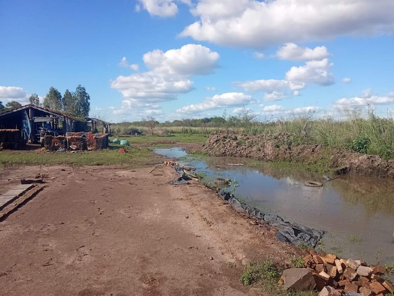 Estructura azul con materiales apilados en un paisaje rural afectado por la crecida del río Tebicuary.