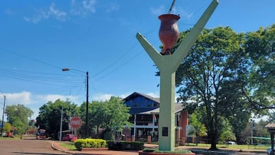 Monumento en un entorno urbano, con estructura verde en un día soleado y árboles al fondo.