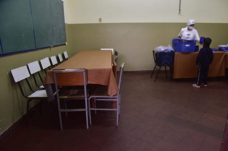 Nutricionista de empresa contratada por el MEC sirve el almuerzo a un niño en la escuela Juan Ramón Dahlquist del barrio Ricardo Brugada.