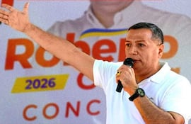 Roberto Cubilla Sanabria hablando al micrófono, con camiseta blanca y gesto enfático en evento político al aire libre.